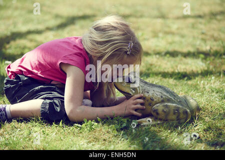 Bimba bionda kissing incantato re di rana Foto Stock