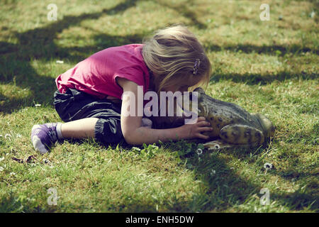 Bimba bionda kissing incantato re di rana Foto Stock