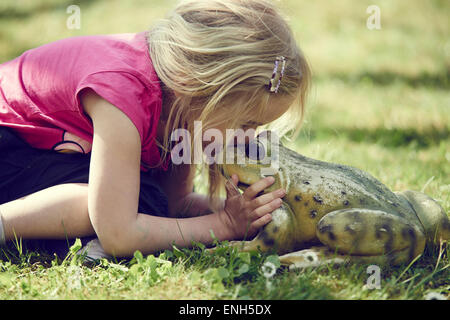 Bimba bionda kissing incantato re di rana Foto Stock