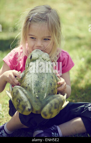 Bimba bionda kissing incantato re di rana Foto Stock