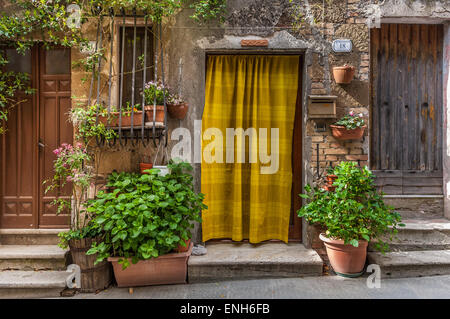 Giallo brillante Tenda a strisce in porta vicino alla parte anteriore ingressi alle residenze rustico a Pitigliano, Provincia di Grosseto, Italia Foto Stock