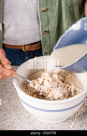 Versando attivata la miscela a base di lievito in una terrina di altri ingredienti del pane, in preparazione per la produzione di grano germogliato pane Foto Stock