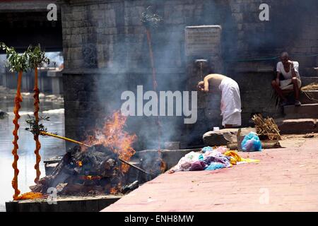 Kathmandu, Nepal. Il 5 maggio, 2015. Un indù l uomo si prende il bagno vicino la Pira come parte dei rituali durante la cremazione dei membri della famiglia che erano morti nel terremoto presso il Tempio di Pashupatinath a Kathmandu, Nepal, il 5 maggio 2015. © Pratap Thapa/Xinhua/Alamy Live News Foto Stock