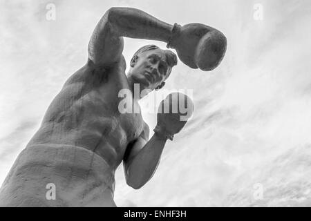 Statua virile boxer con guanti sferrare pugni in monocromia Foto Stock