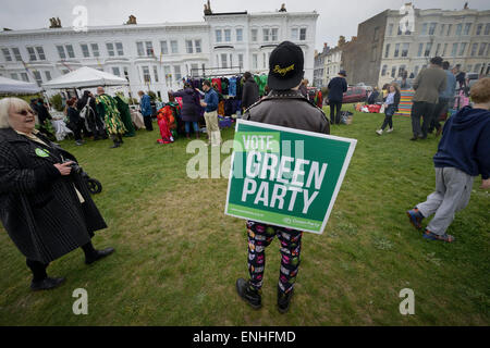 Un uomo che indossa un voto verde targhetta di partito durante le elezioni generali passeggiate fra un gruppo di persone a un evento in Hastings, Sussex, Inghilterra. Foto Stock