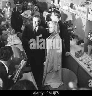 Actrice americano Marilyn Monroe e Sir Laurence Olivier cercano rifugio dai fotografi in attesa dietro un contatore all'aeroporto di Heathrow. Monroe aveva appena volato a Londra con il marito, drammaturgo Arthur Miller che è raffigurato dietro con Vivien Leigh Foto Stock