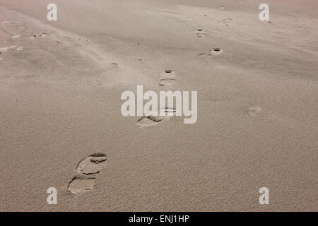 Piedi stampe lead off nella sabbia sulla spiaggia. Foto Stock