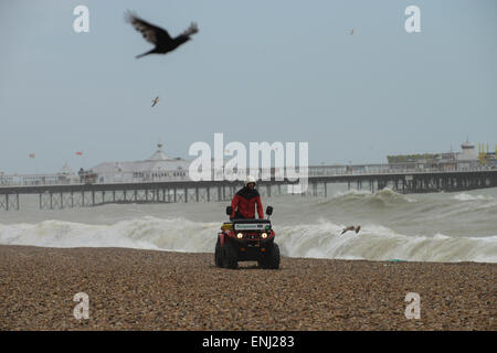 Durante condizioni tempestose un bagnino di pattuglie spiaggia su di una moto quad di fronte al molo di Brighton a Brighton, East Sussex, Inghilterra. Foto Stock