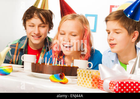 Ragazza bionda si brucia candele sulla sua torta di compleanno Foto Stock