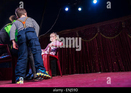 Basso angolo vista della ragazza sorridente indossando Clown compongono seduto nella sedia rossa sul palco con ragazzo e uomo guardando, copia spazio per Ri Foto Stock