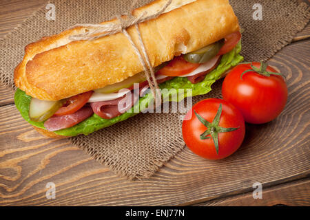 Sandwich con insalata, prosciutto, formaggio e pomodori sul tavolo di legno Foto Stock