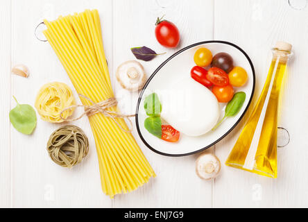 Mozzarella, pomodoro e basilico e olio d'oliva sul tavolo di legno Foto Stock