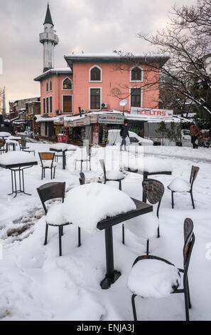 La neve e il ghiaccio che ricopre il cafe e i tavoli e le sedie in Karakoy, Istanbul, Turchia. Foto Stock