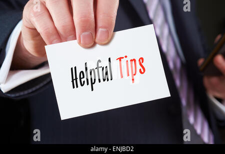 Un imprenditore in possesso di un biglietto da visita con le parole, suggerimenti utili, scritto su di esso. Foto Stock