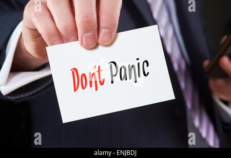Un imprenditore in possesso di un biglietto da visita con le parole, non fatevi prendere dal panico, scritto su di esso. Foto Stock