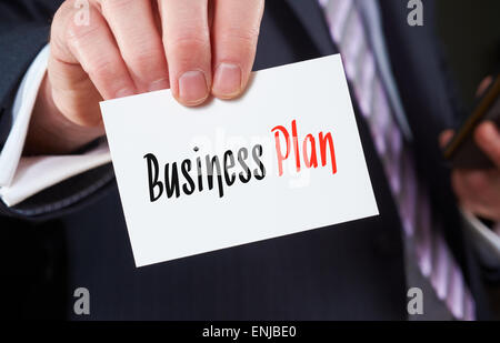 Un imprenditore in possesso di un biglietto da visita con le parole, Business Plan, scritto su di esso. Foto Stock