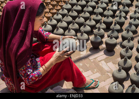 Bhaktapur, Nepal - 20 marzo 2015: donna immissione potteries a secco sulla piazza di ceramiche. Foto Stock