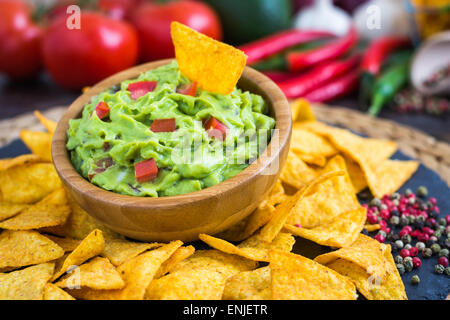 Guacamole nella ciotola di legno con tortilla chips e Ingredienti Foto Stock