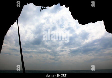 Un scalatore scale a mare grotta sulle scogliere vicino a Swanage, Dorset, England, Regno Unito, Europa Foto Stock