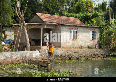 Una donna il suo lavaggio biancheria nelle lagune del Kerala nel sud-ovest dell'India Foto Stock