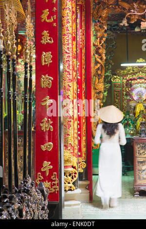 Donna che indossa ao dai abito a Phuoc un Hoi Quan Pagoda, Cholon, Ho Chi Minh City, Vietnam, Indocina, Asia sud-orientale, Asia Foto Stock