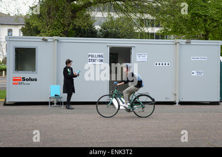 Una donna passa la bicicletta davanti a un edificio portabile Portakabin che è stato istituito come un seggio per le elezioni generali del 2015 a Preston Park, Brighton, East Sussex, Inghilterra. Foto Stock