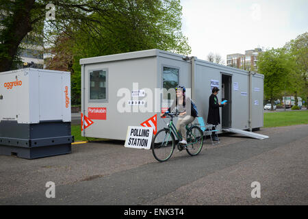 Un ciclista passa davanti ad un edificio portabile Portakabin che è stato istituito come un seggio per le elezioni generali del 2015 a Preston Park, Brighton, East Sussex, Inghilterra. Foto Stock