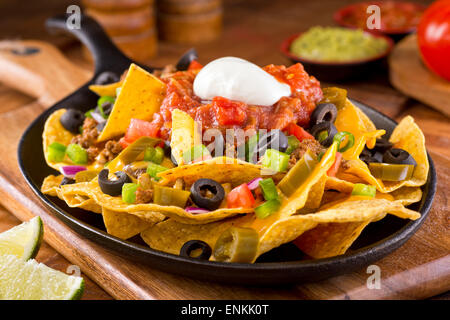 Una piastra di deliziose tortillas nachos con formaggio fuso e salsa di carne di manzo macinata, i peperoncini jalapeno, cipolla rossa, cipollotti, pomodoro, b Foto Stock