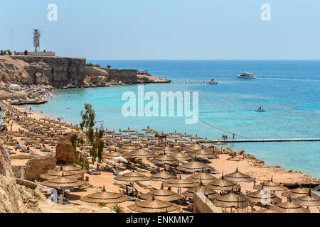 Nella foto una tipica spiaggia egiziano nel Mar Rosso con legno e ombrelloni di paglia e mare turchese. Foto Stock