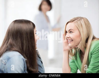 Studente ragazze spettegolare a scuola Foto Stock