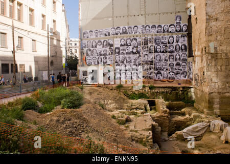 Foto di volti di persone locali della parte vecchia di Barcellona sono vedere appeso accanto alle mura storiche della città.. Foto Stock