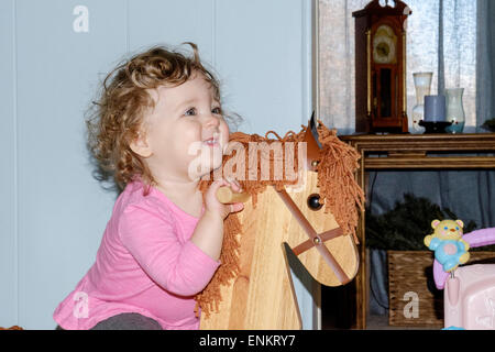 A dieci mesi di old Baby girl ride mentre il suo cavallo di legno cavallo a dondolo. Foto Stock