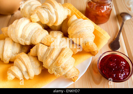Freschi Fatti in casa mini croissant con marmellata (marmellata) sul tavolo di legno Foto Stock