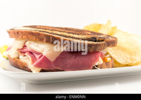 Ruben classico panino sulle pumpernickel swirl pane di segale. Un abbondante pasto con un lato della salamoia e trucioli Foto Stock