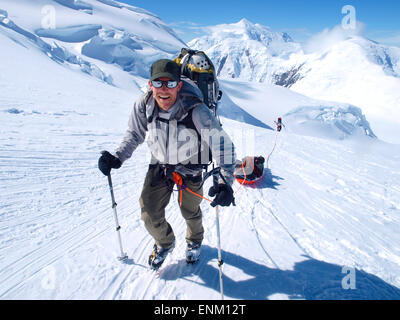 Mountain ranger Brian Scheele su questo modo di Ventoso angolo sul Monte McKinley, conosciuto anche come Denali in Alaska. Egli sta tirando una slitta, che insieme con il suo zaino pesante è contenente tutto l'ingranaggio come tende, vestiti e cibo. Foto Stock