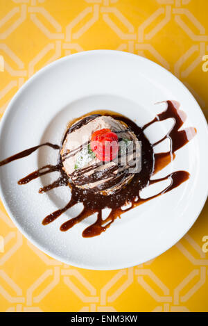 Colpo di overhead di frittelle con il Tiramisù panna e cioccolato su una piastra bianca con uno sfondo giallo Foto Stock