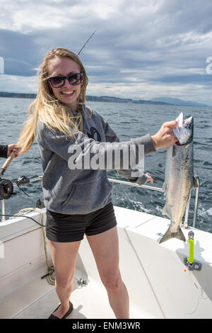 Nord America, Canada, British Columbia, Discovery Passage, Vancouver Island, Pesca al salmone, donna che tiene catturato Coho salmone Foto Stock