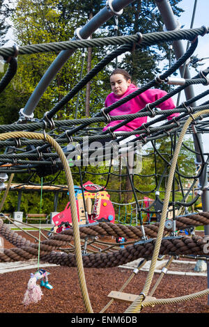 Giovane ragazza in appoggio sulla fune mesh di un telaio di arrampicata a Vancouver in Canada Foto Stock