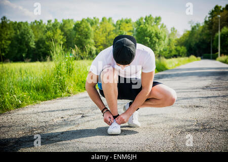 Bel giovane legatura di calzature sportive prima di andare in esecuzione Foto Stock