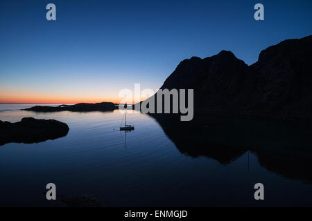 Barca a vela ancoraggio in estate al crepuscolo Buvågen bay a Helle sulla punta occidentale di Moskenesøy, Isole Lofoten in Norvegia Foto Stock