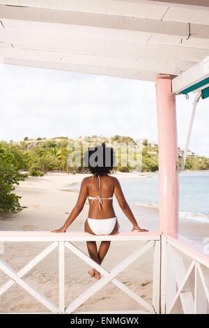 Giovane donna nera seduta sul treno al bar sulla spiaggia, vista posteriore. Foto Stock