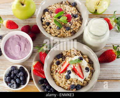 Muesli, frutti di bosco freschi e yogurt per la colazione su un sfondo di legno Foto Stock