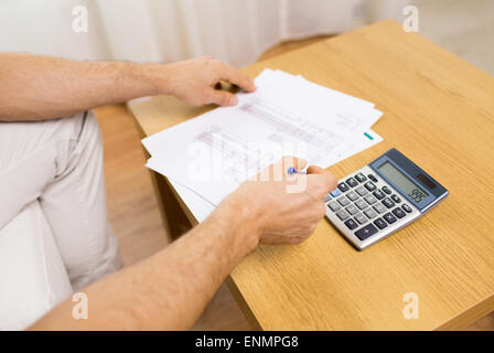 Close up dell'uomo con le carte e calcolatrice a casa Foto Stock