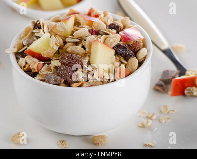 Muesli e frutta per colazione in una ciotola bianco. Messa a fuoco selettiva Foto Stock