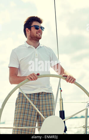 Giovane uomo in occhiali da sole il volante su yacht Foto Stock