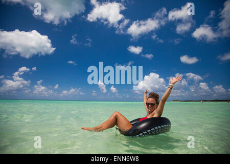 Una giovane donna che indossa un bikini galleggia su un tubo gonfiabile in acque turchesi mentre è in vacanza in Cayo Coco, Cuba.
