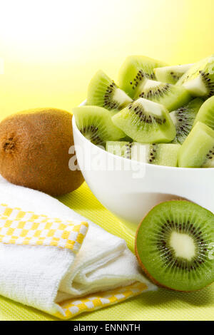 Sani e freschi di kiwi ciotola con un puntello di giallo e sfondo soleggiato Foto Stock