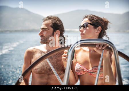 Bella coppia in barca a vela, giovane famiglia felice dietro il timone di lusso trasporto acqua, divertendosi in mare Foto Stock