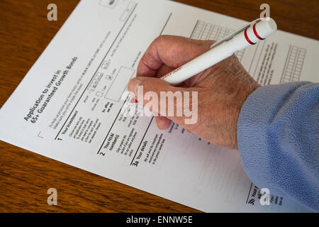 Titolare di pensione o di rendita femmina completando il modulo di richiesta è investire in 65+ garantiti legami di crescita Foto Stock