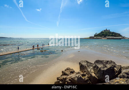 I vacanzieri di attendere per la marea di cadere in modo da poter attraversare a St Michael's Mount in Cornovaglia Foto Stock